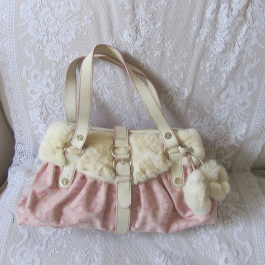 Pink handbag with white fur trim on a textured surface