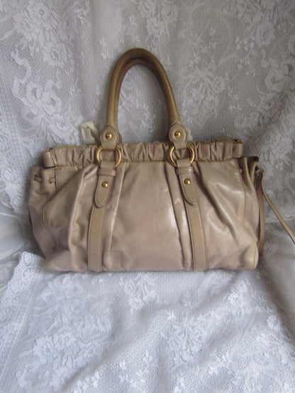 Beige handbag with gold accents on a white lace background