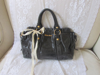 Black handbag with gold accents on a textured white surface