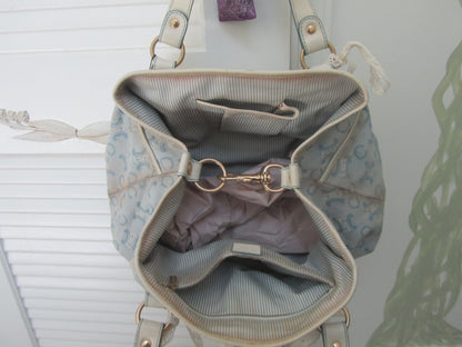 Light blue handbag with gold accents on a white background