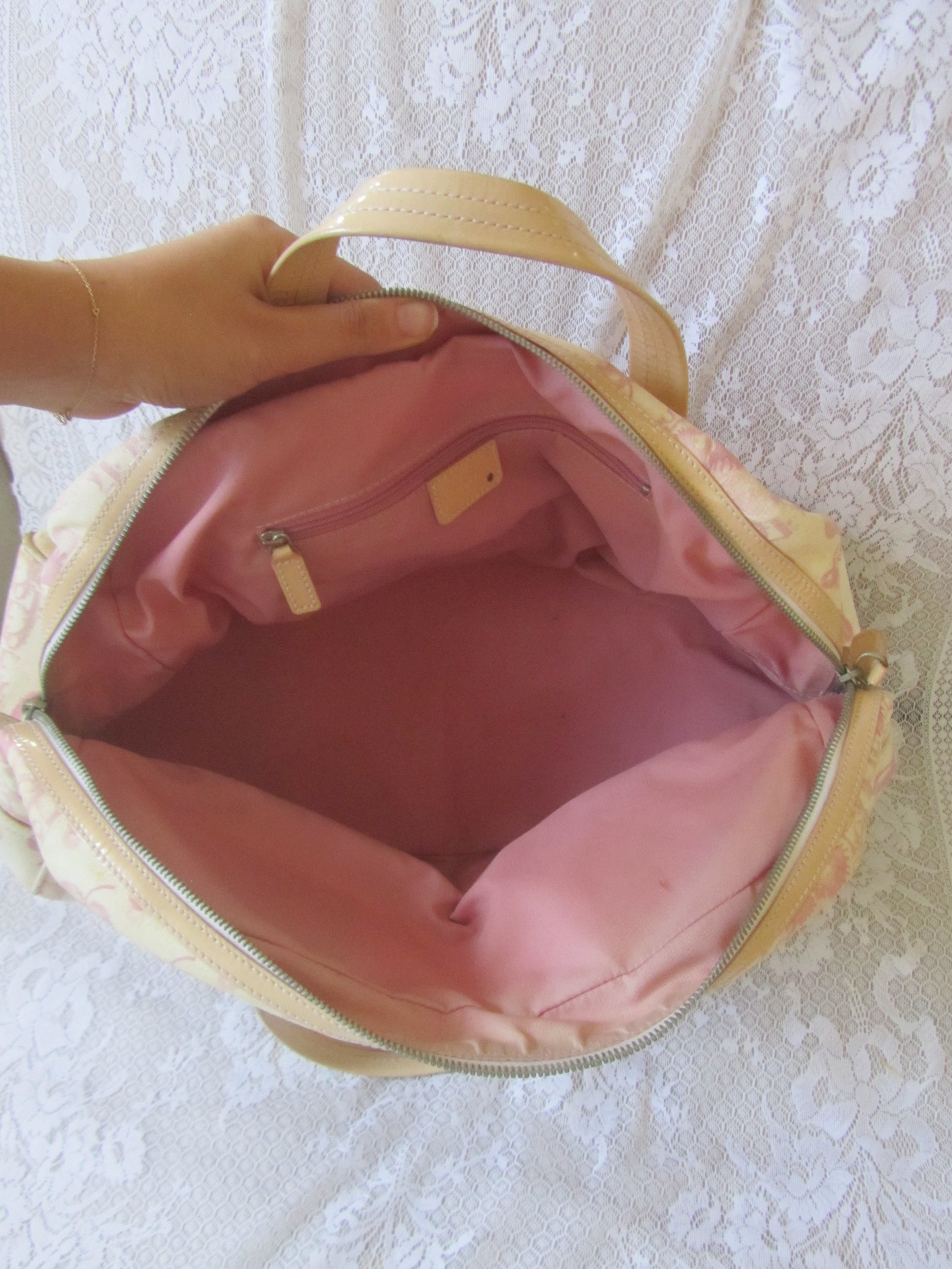Beige handbag with pink interior on a textured white surface