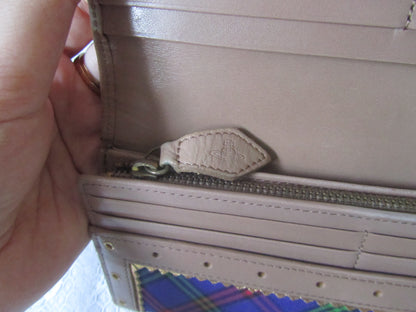 Close-up of a beige leather wallet with a zipper, held by a hand.