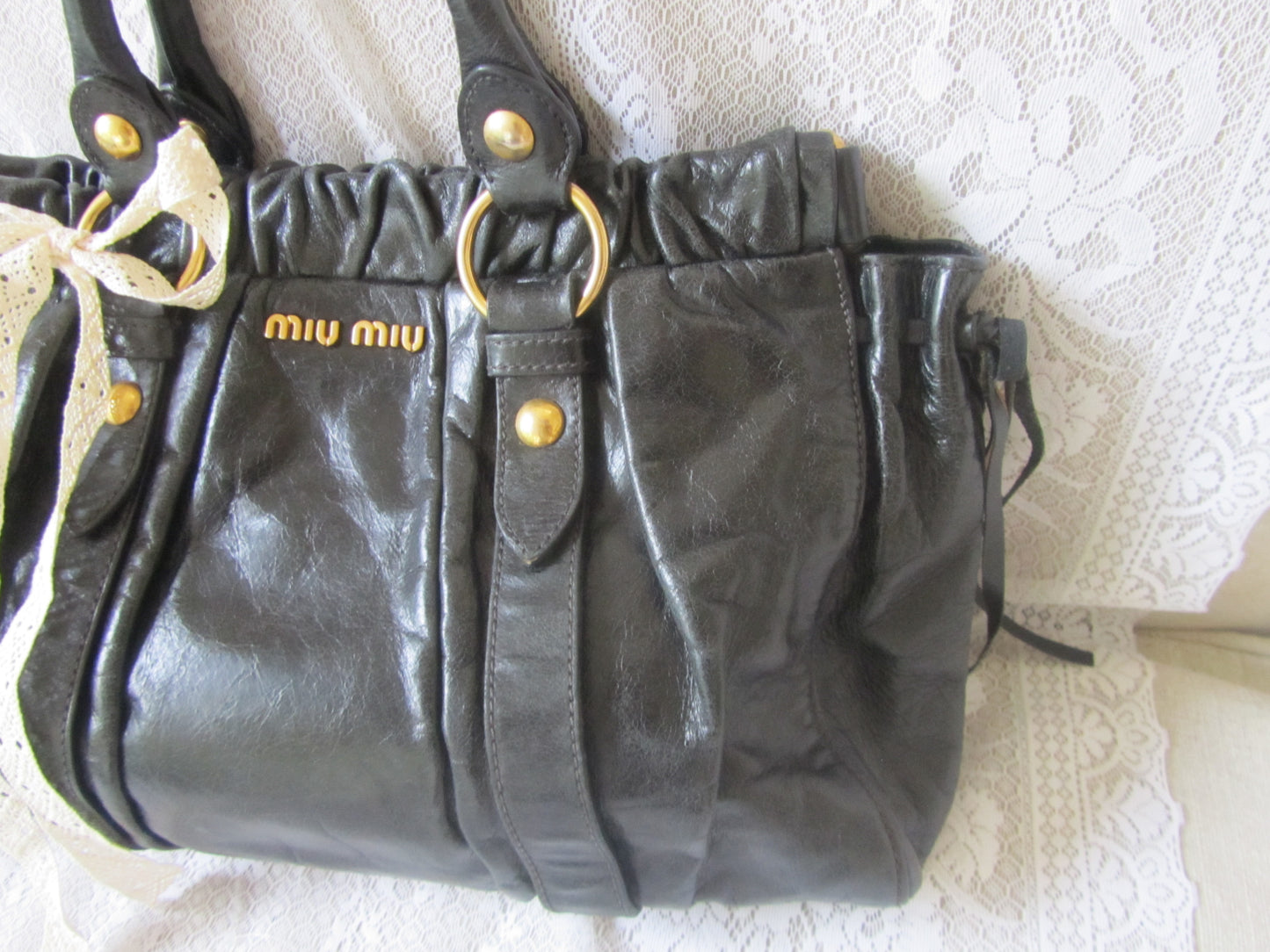 Black handbag with gold accents on a textured white surface