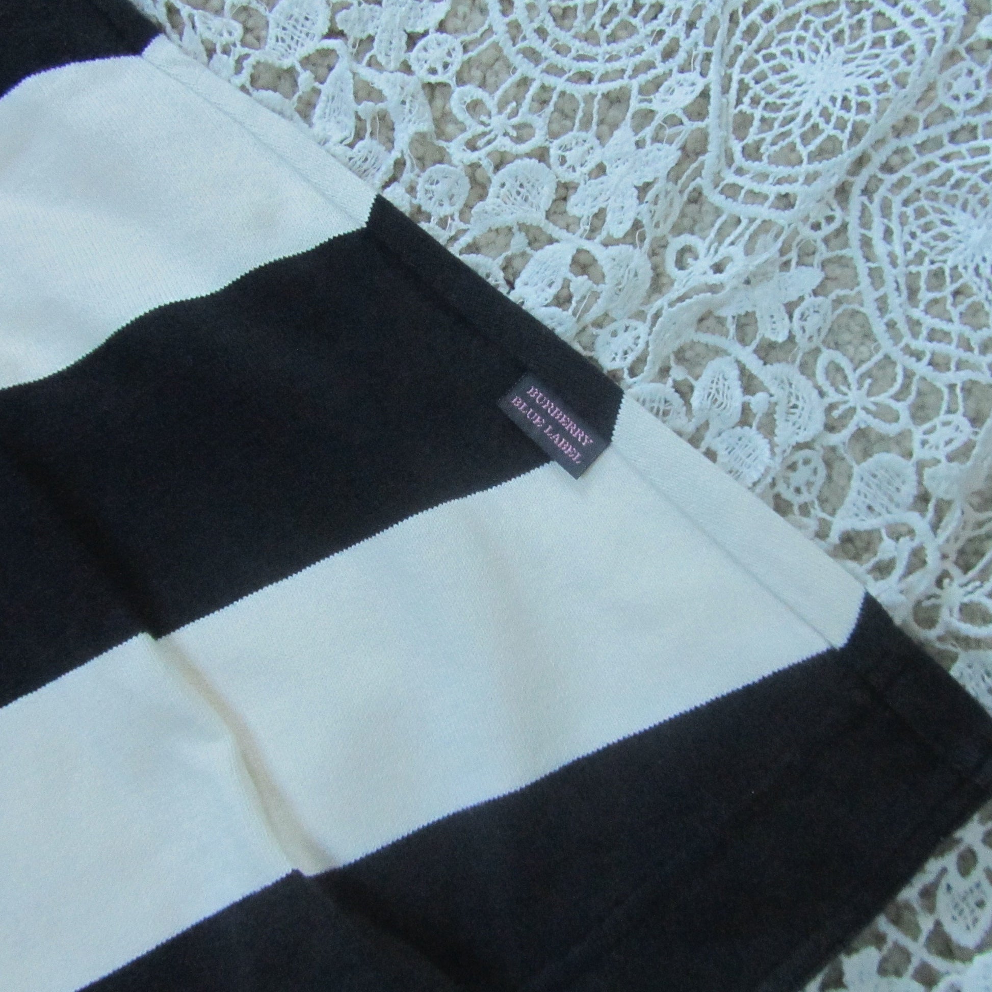 Black and white striped fabric with a brand label on a lace background