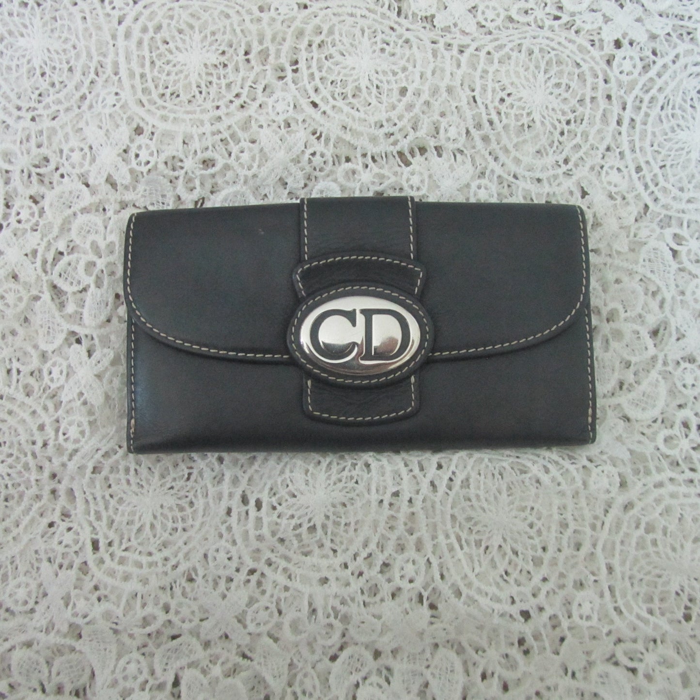 Black wallet with a brand logo on a textured white background