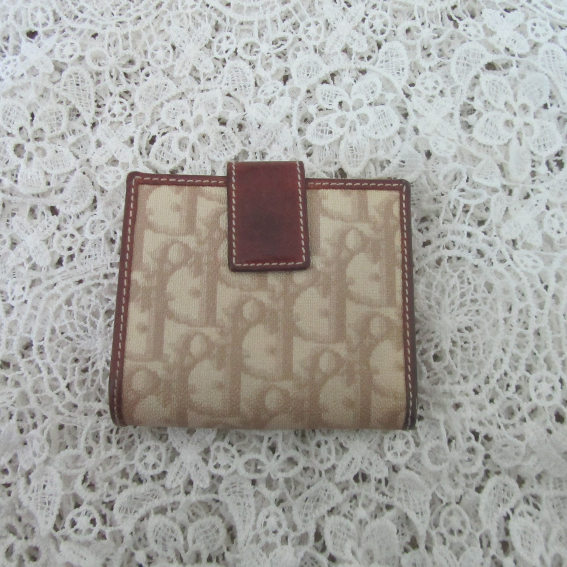 Beige wallet with brown accents on a white lace background