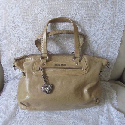 Beige handbag with decorative elements on a white lace fabric background