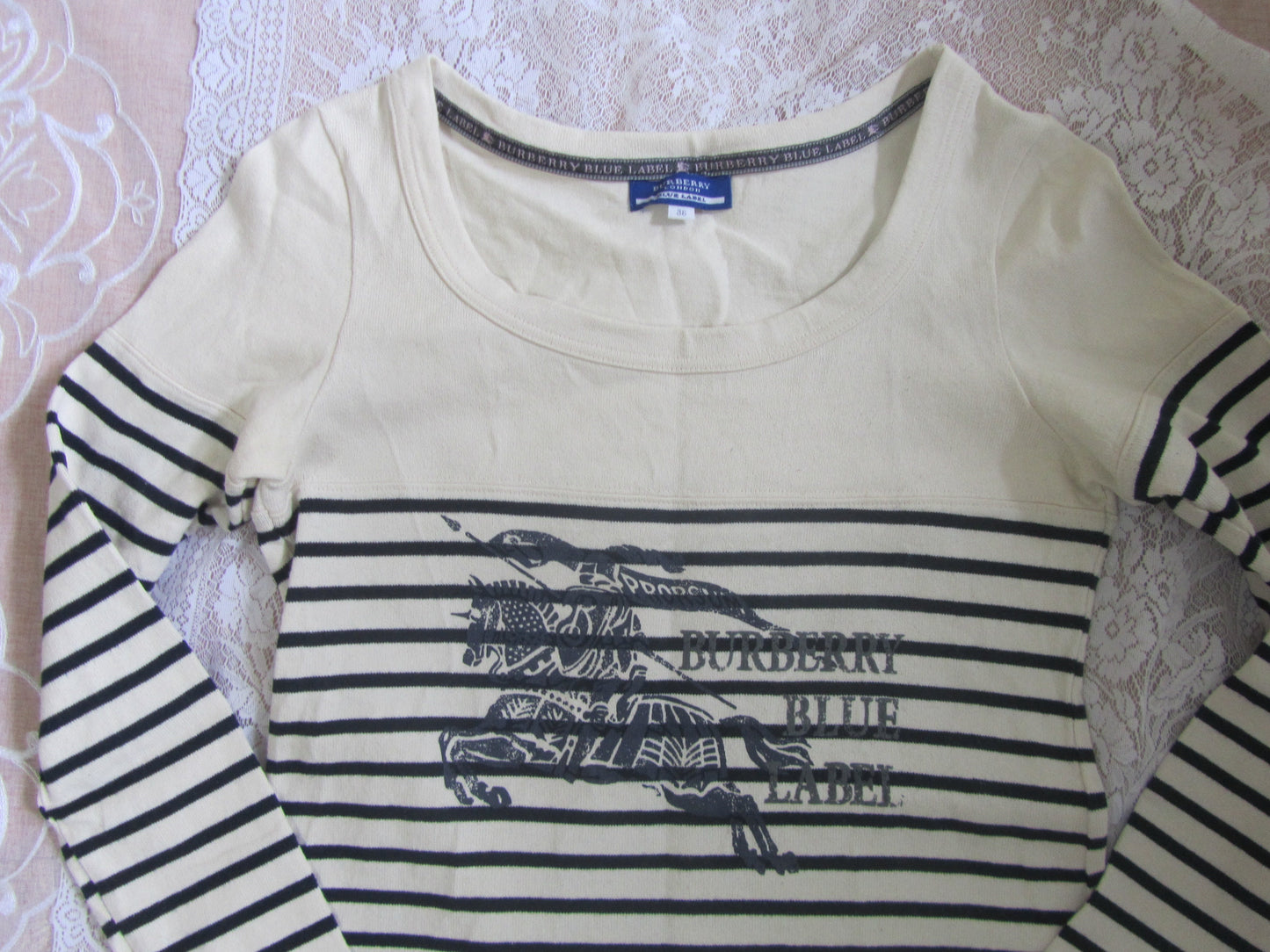 Long-sleeve shirt with striped pattern and brand logo on a textured surface