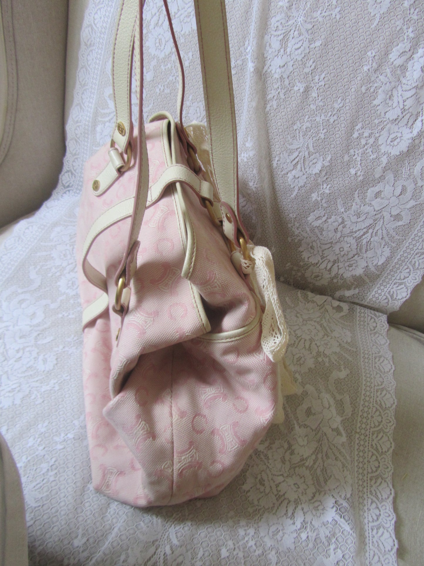 Pink drawstring bag with gold accents on a textured beige surface