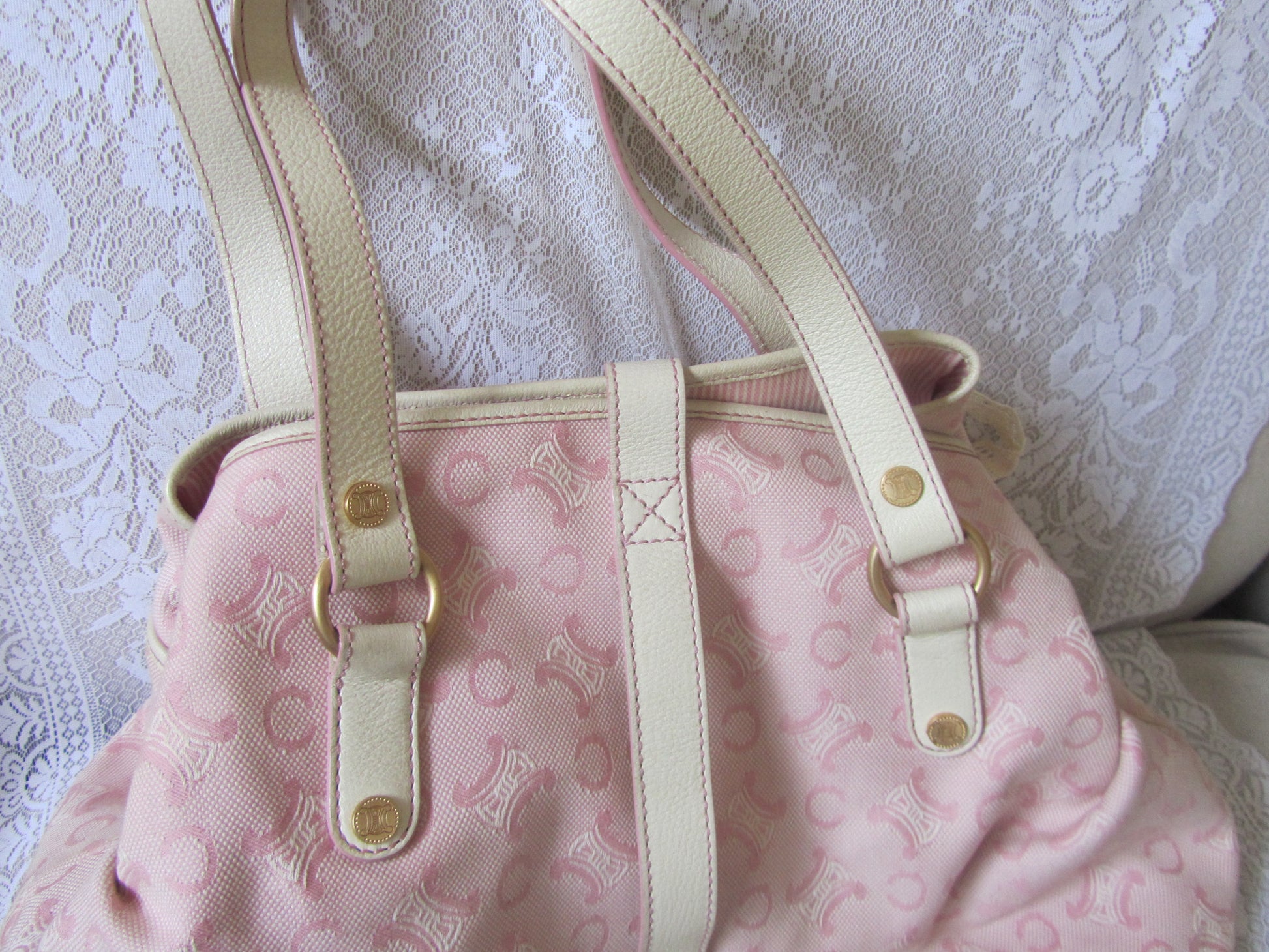 Pink handbag with gold accents on a textured white background
