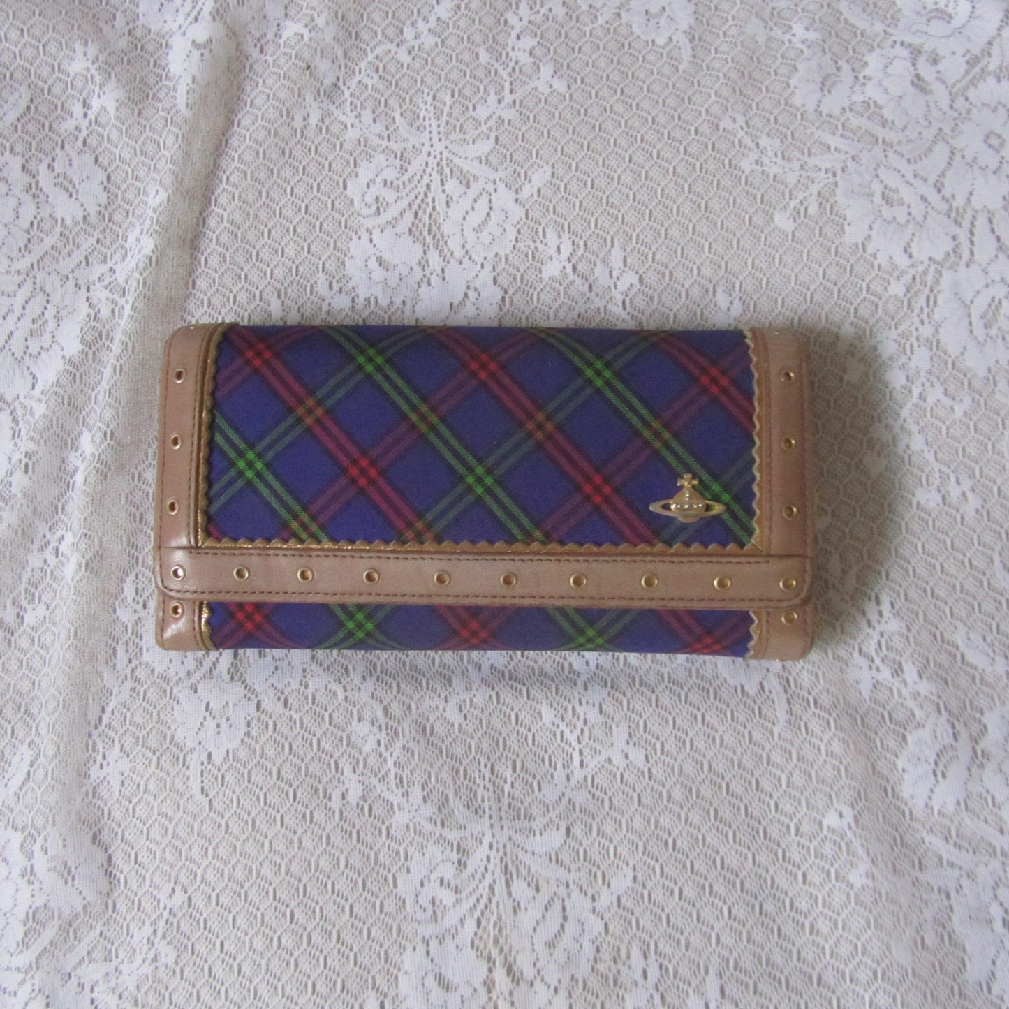 Plaid wallet with brand logo on a textured white surface