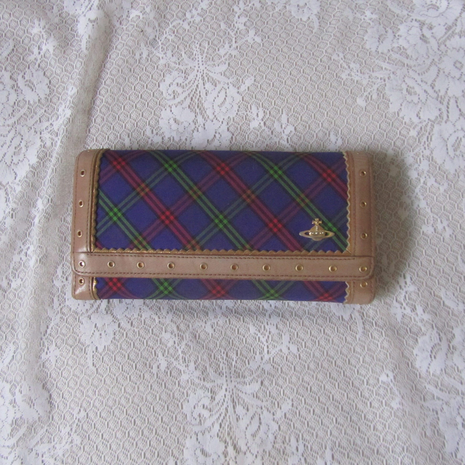 Plaid wallet with brand logo on a textured white surface