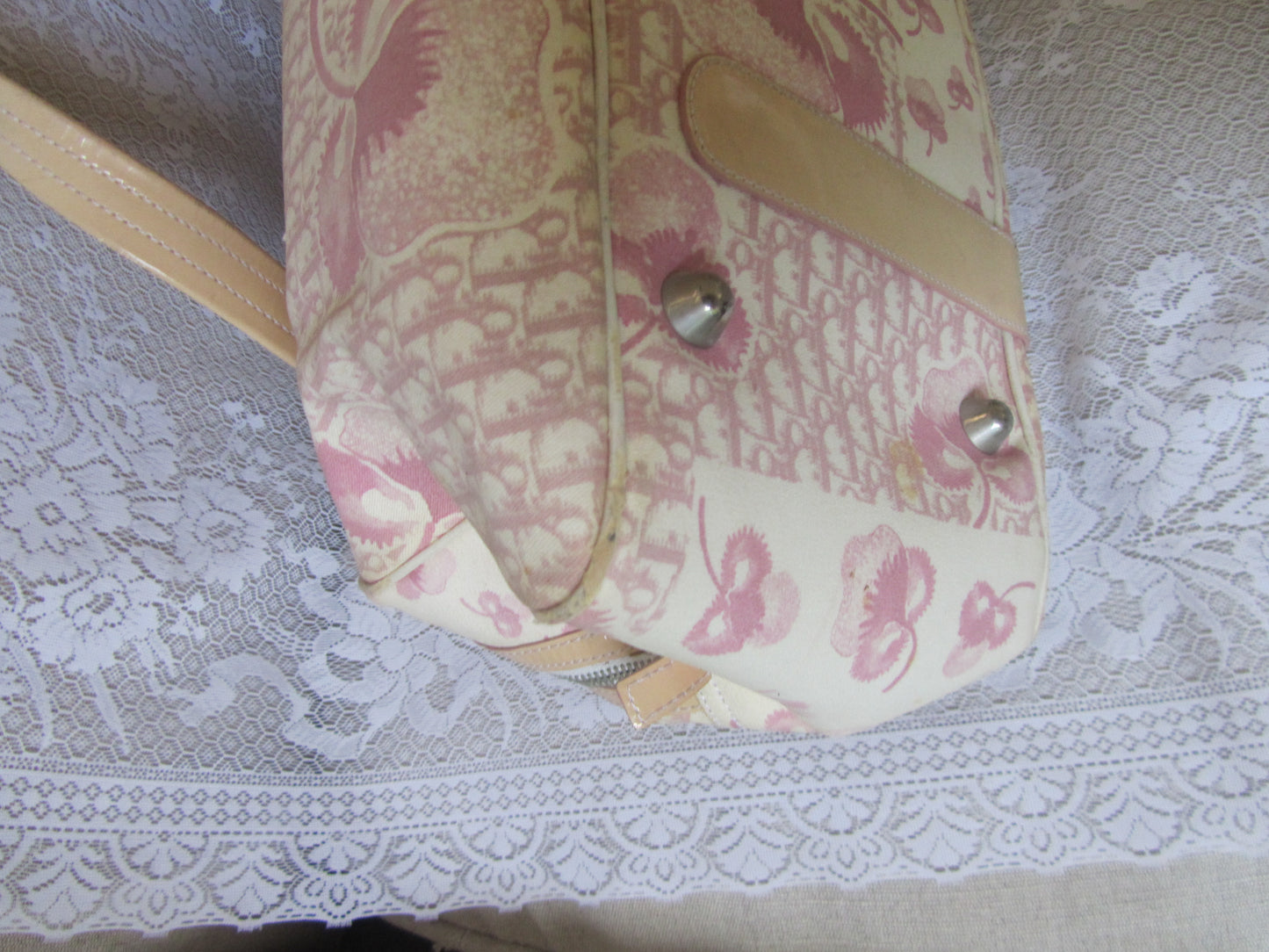 Floral-patterned bag with metallic buttons on a lace surface
