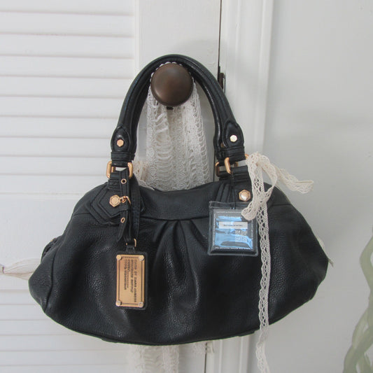 Black handbag with a tag on a white background