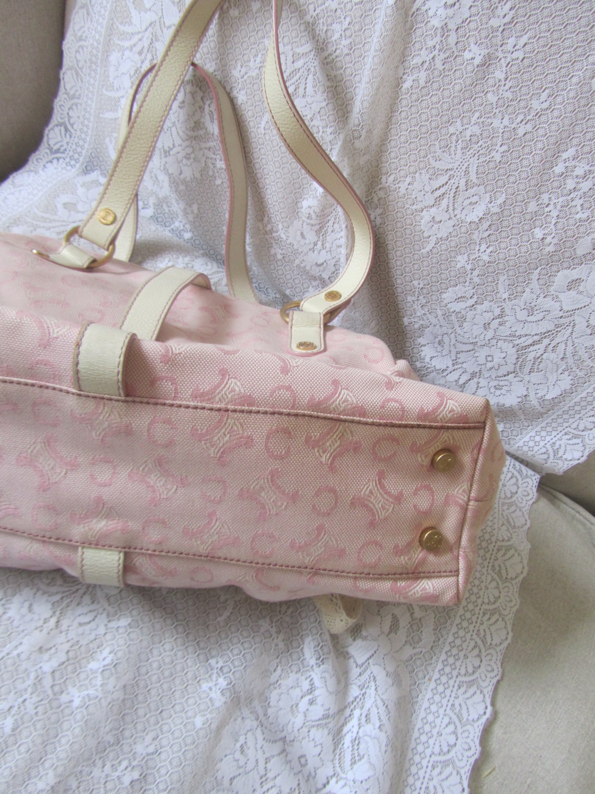 Pink handbag with gold accents on a white lace fabric background