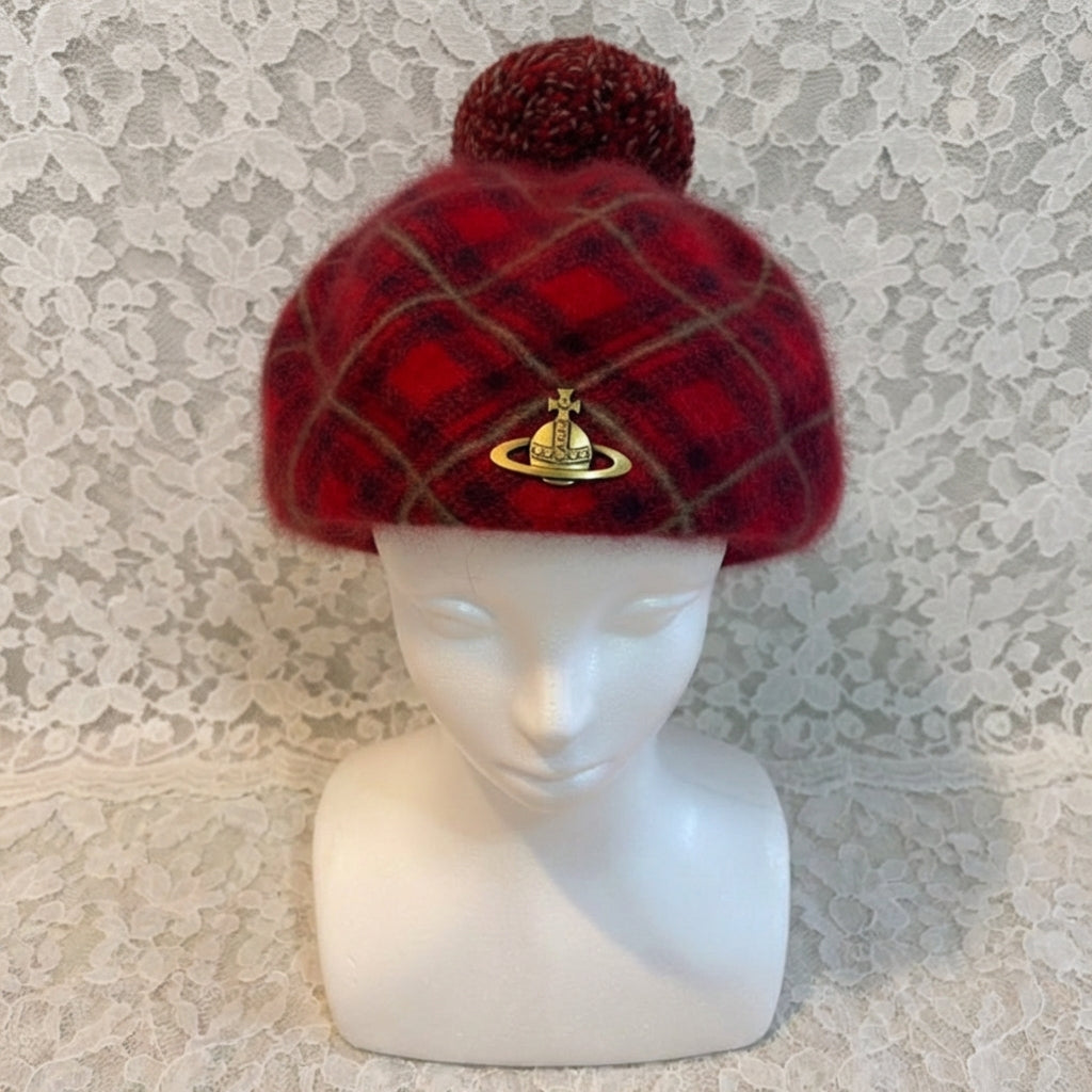 Red plaid beanie with a pom-pom on a mannequin head against a textured white background