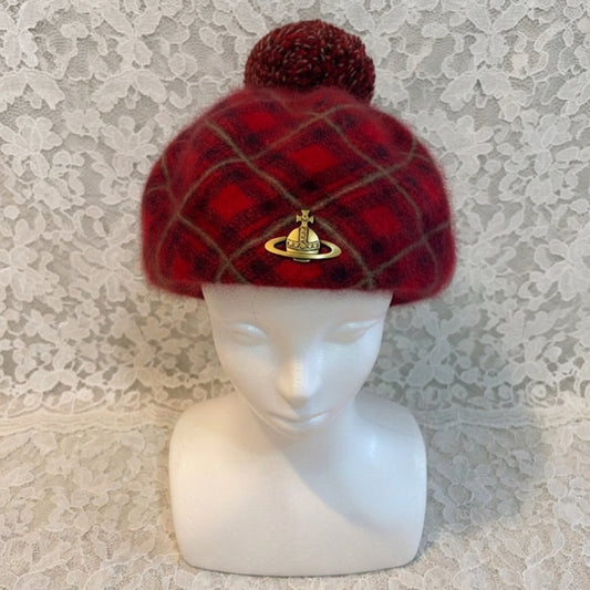 Red plaid beanie with a pom-pom on a mannequin head against a textured white background