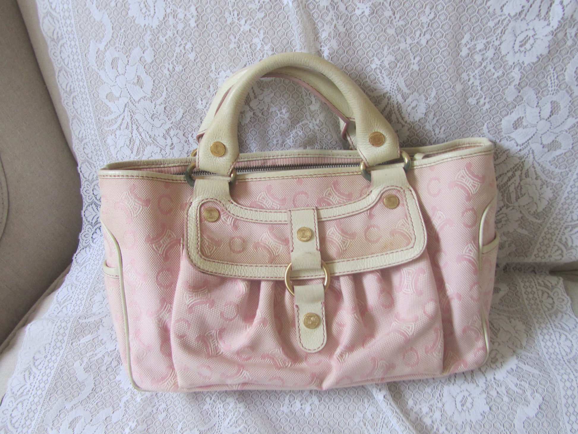 Pink handbag with beige accents on a textured white surface