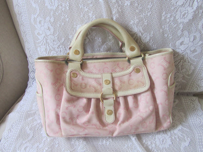 Pink handbag with beige accents on a textured white surface