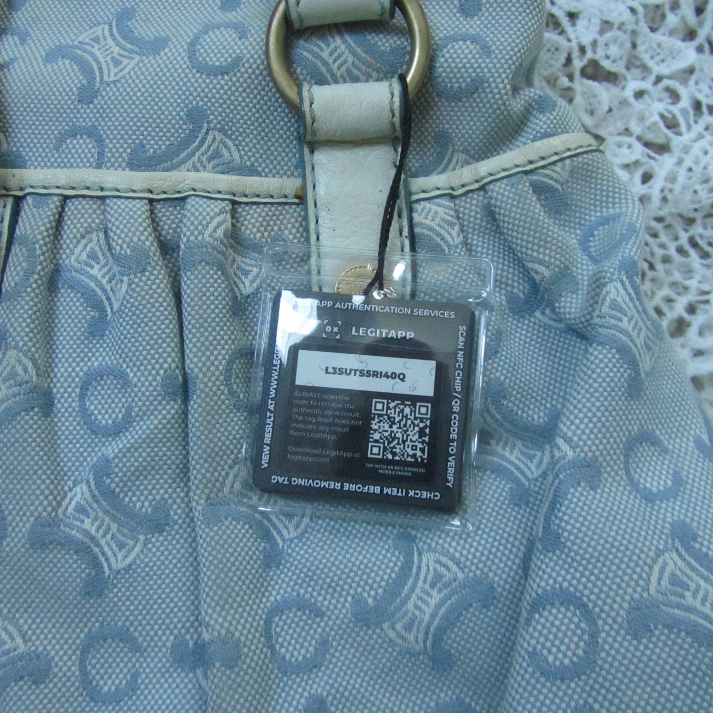 Patterned handbag with a clear tag featuring a QR code on a lace background