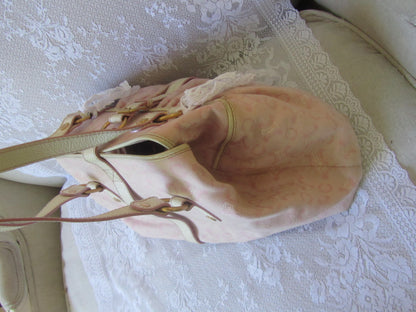 Beige handbag with a green strap on a textured white surface