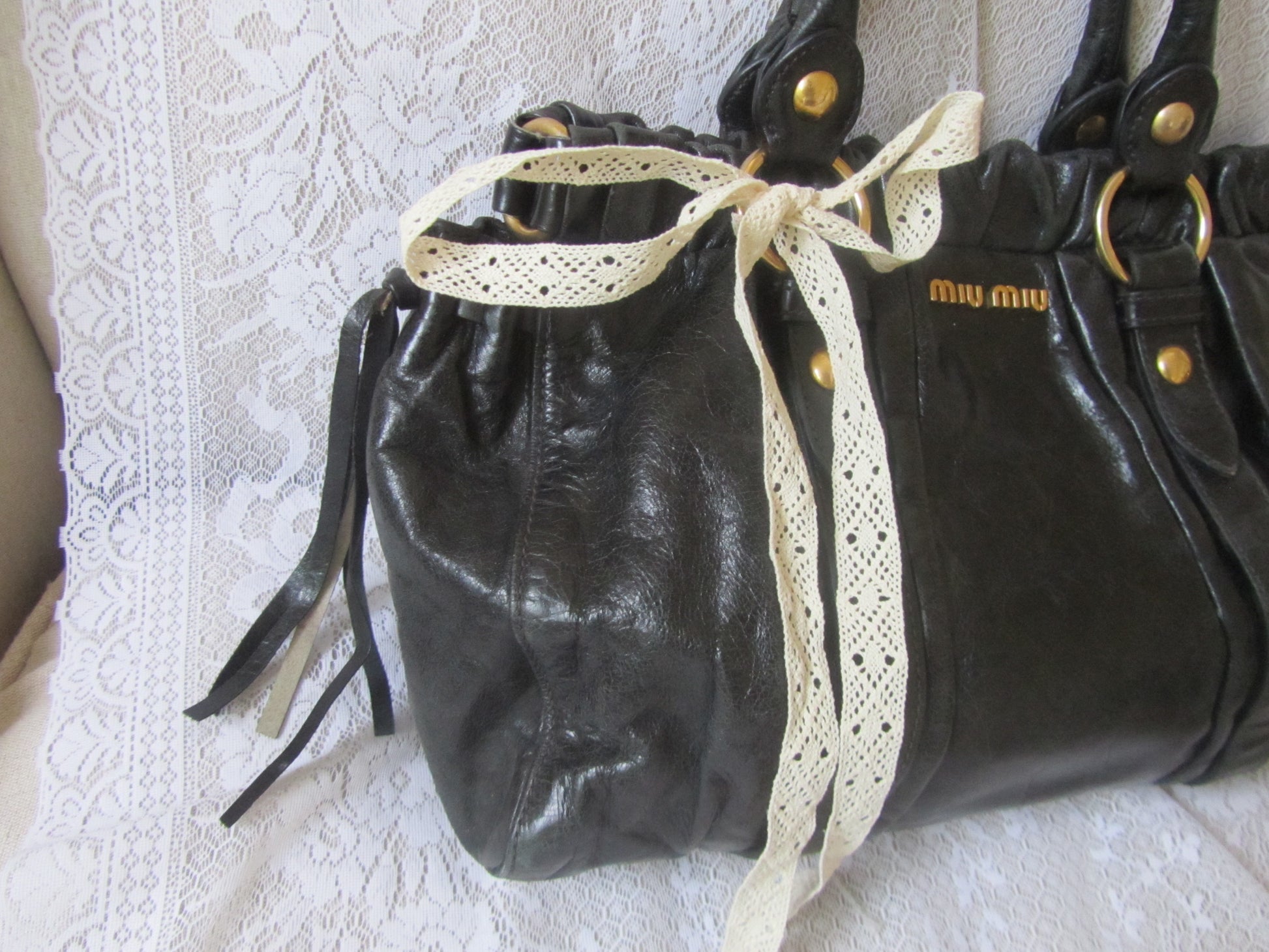 Black leather handbag with a lace ribbon on a textured white surface