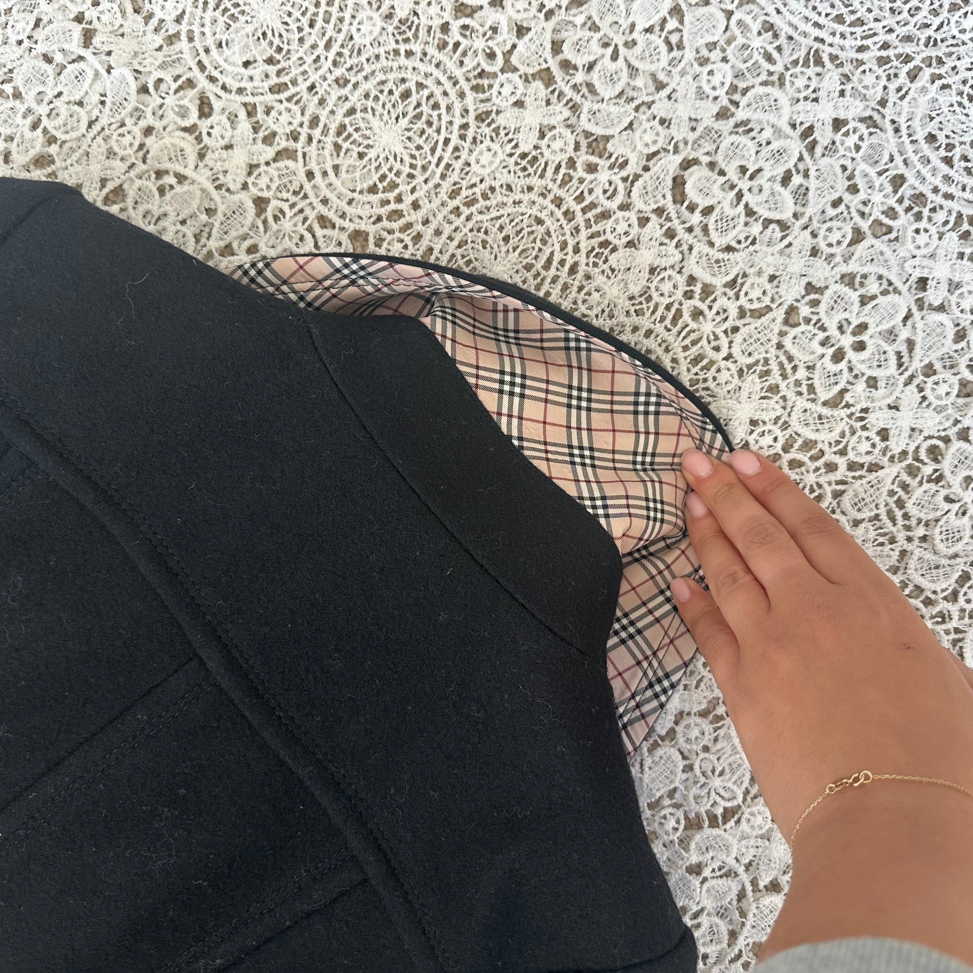 Close-up of a black garment with plaid lining against a lace background
