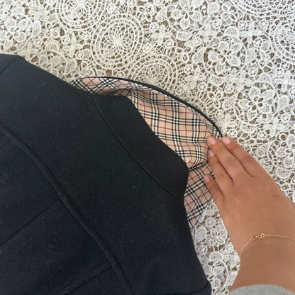 Close-up of a black garment with plaid lining against a lace background