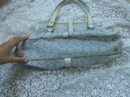 Light blue patterned handbag held by a hand on a lace tablecloth