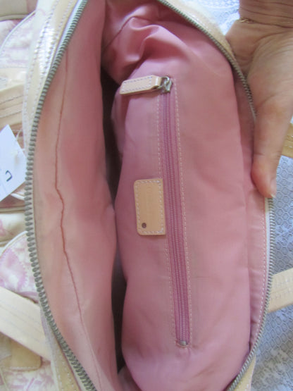 Pink bag with a visible brand label held by a hand on a textured surface.