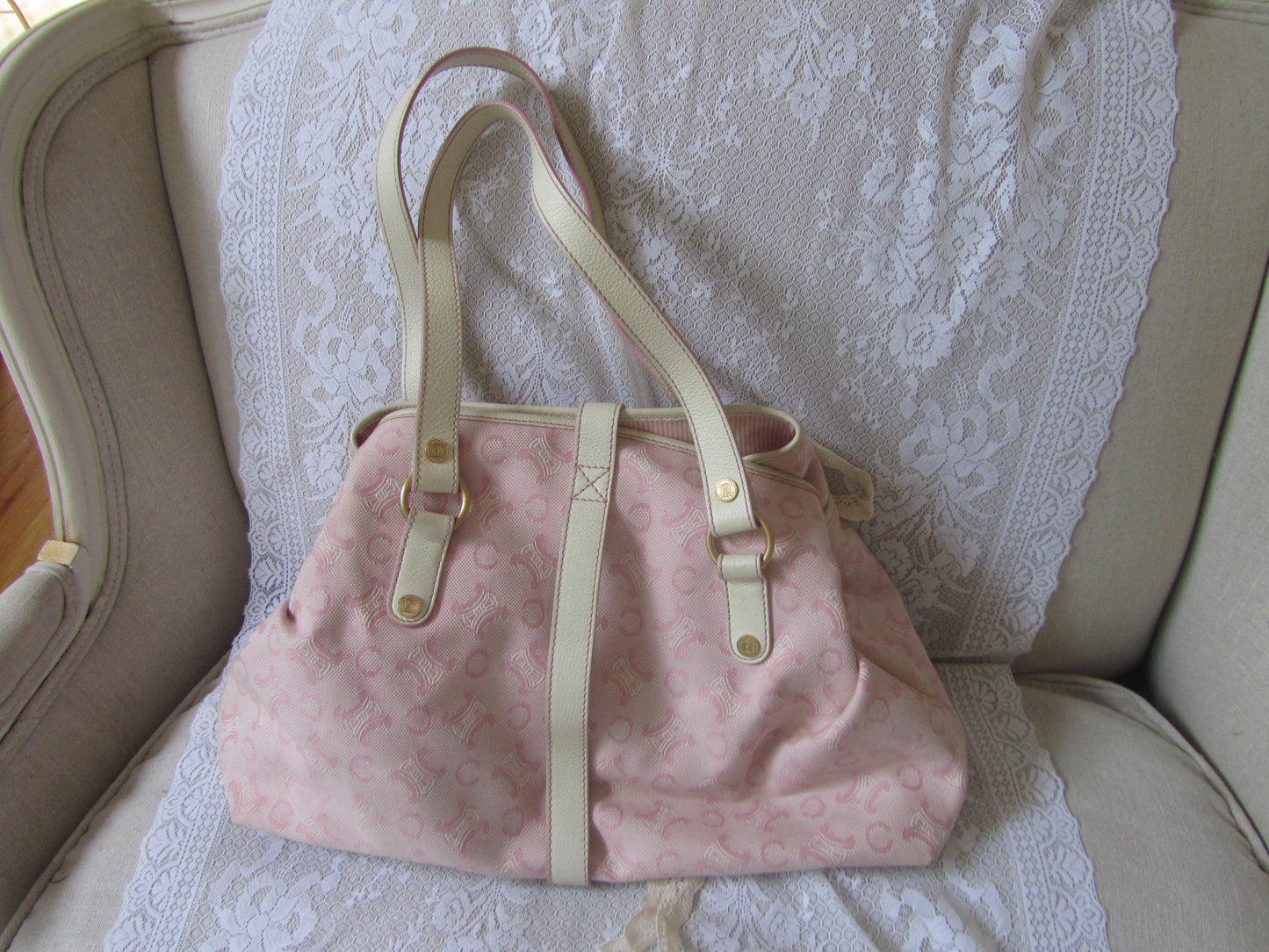 Pink handbag with beige straps on a lace-covered surface