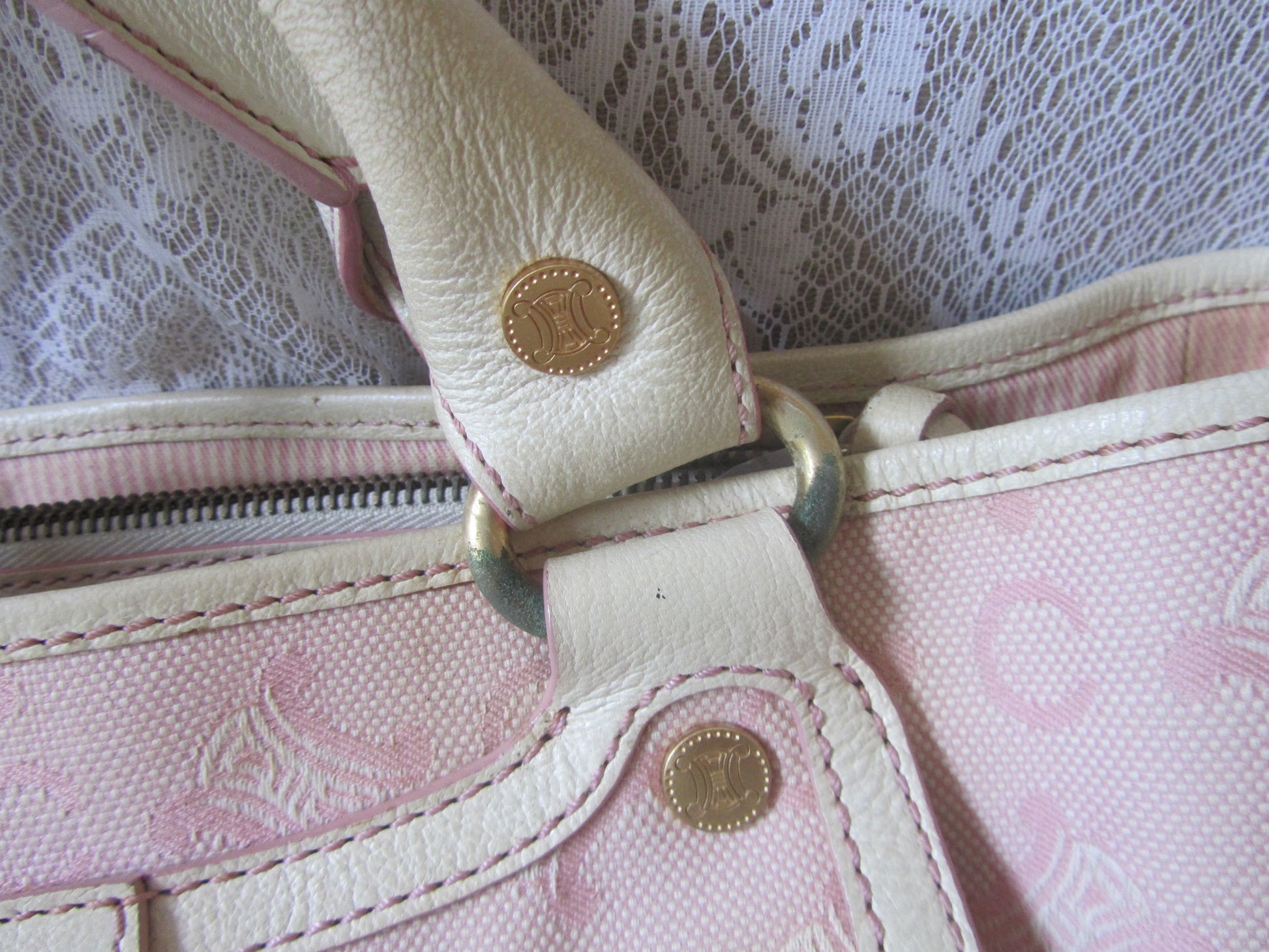 Close-up of a pink handbag with gold hardware on a lace background