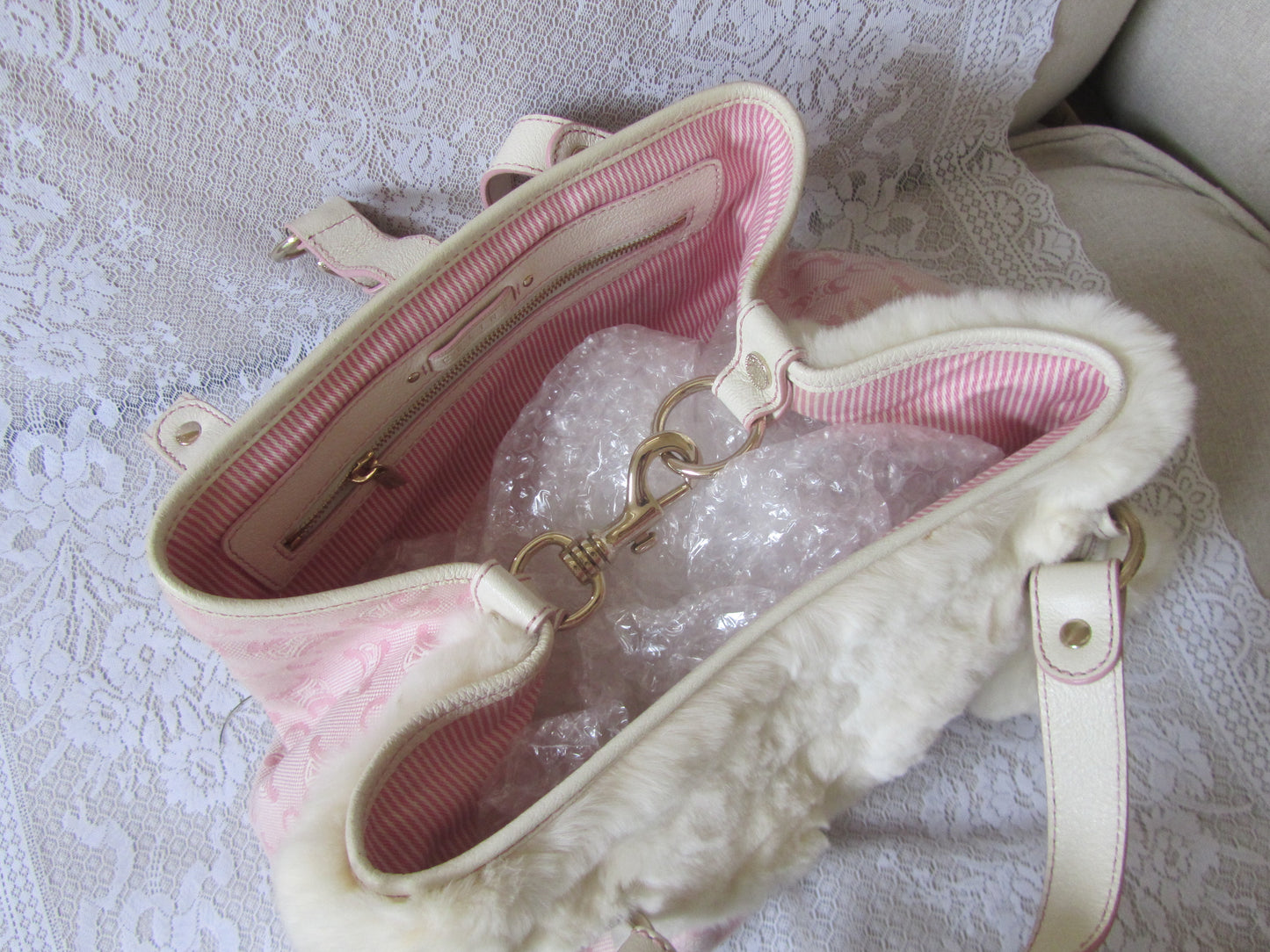Pink handbag with white interior on a textured surface