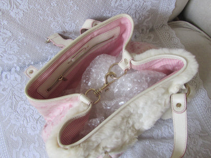 Pink handbag with white interior on a textured surface