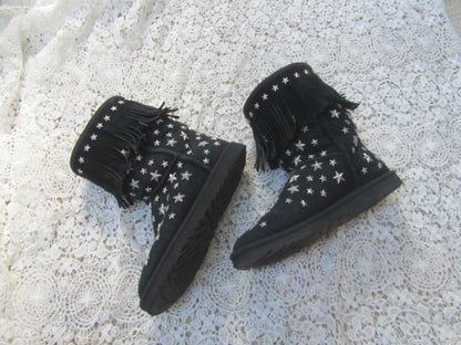 Black boots with star patterns on a textured white surface