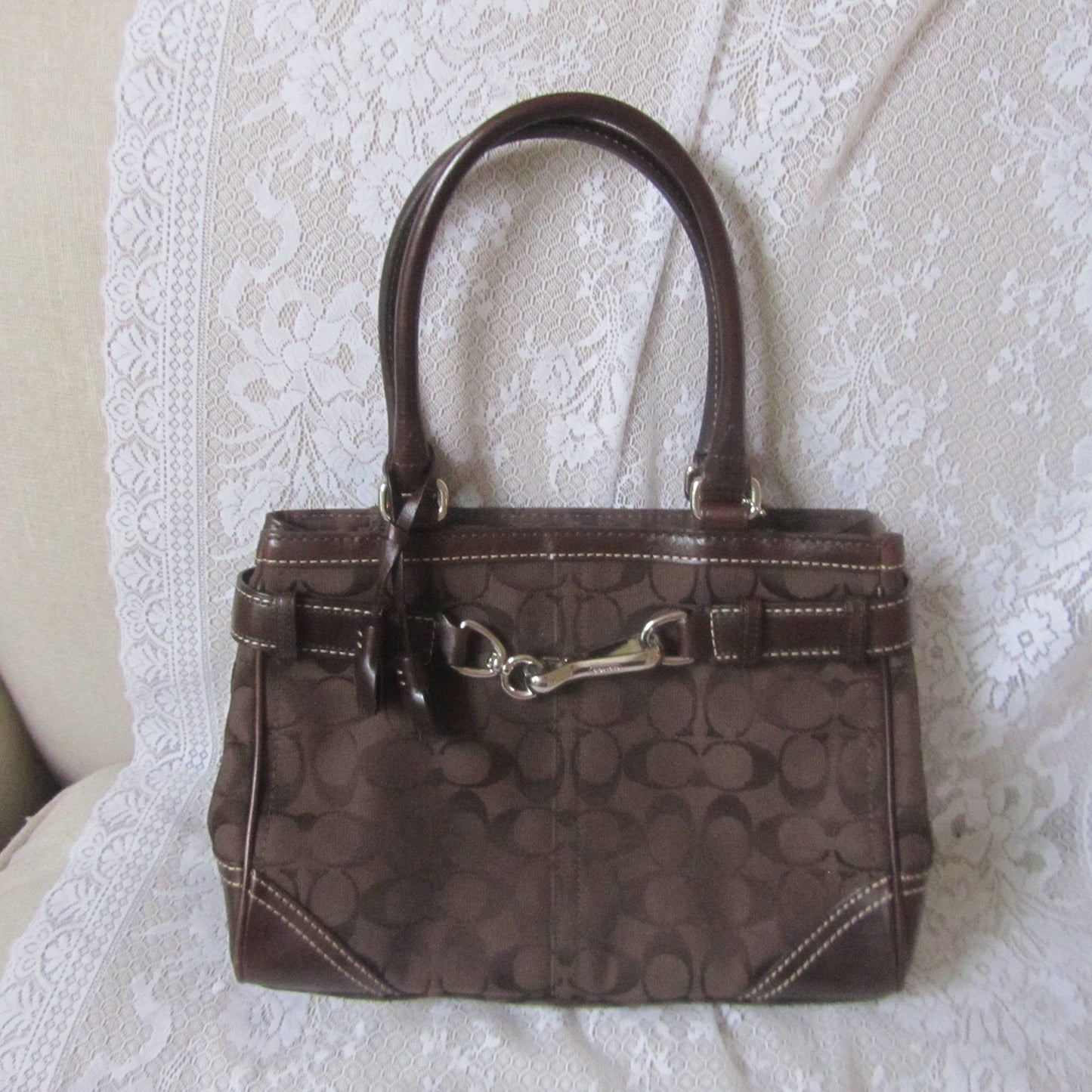 Brown handbag with a visible brand logo on a white textured surface