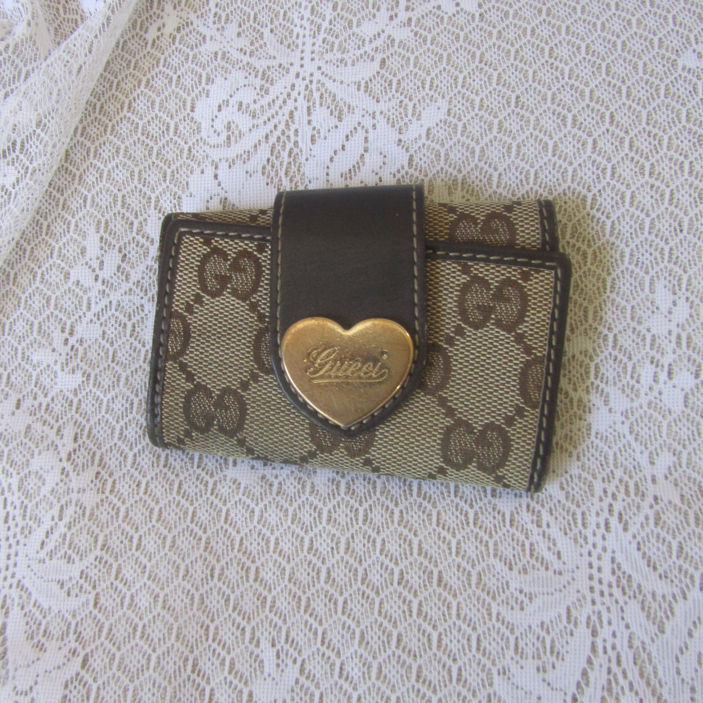 Small Gucci wallet with heart emblem on a lace background