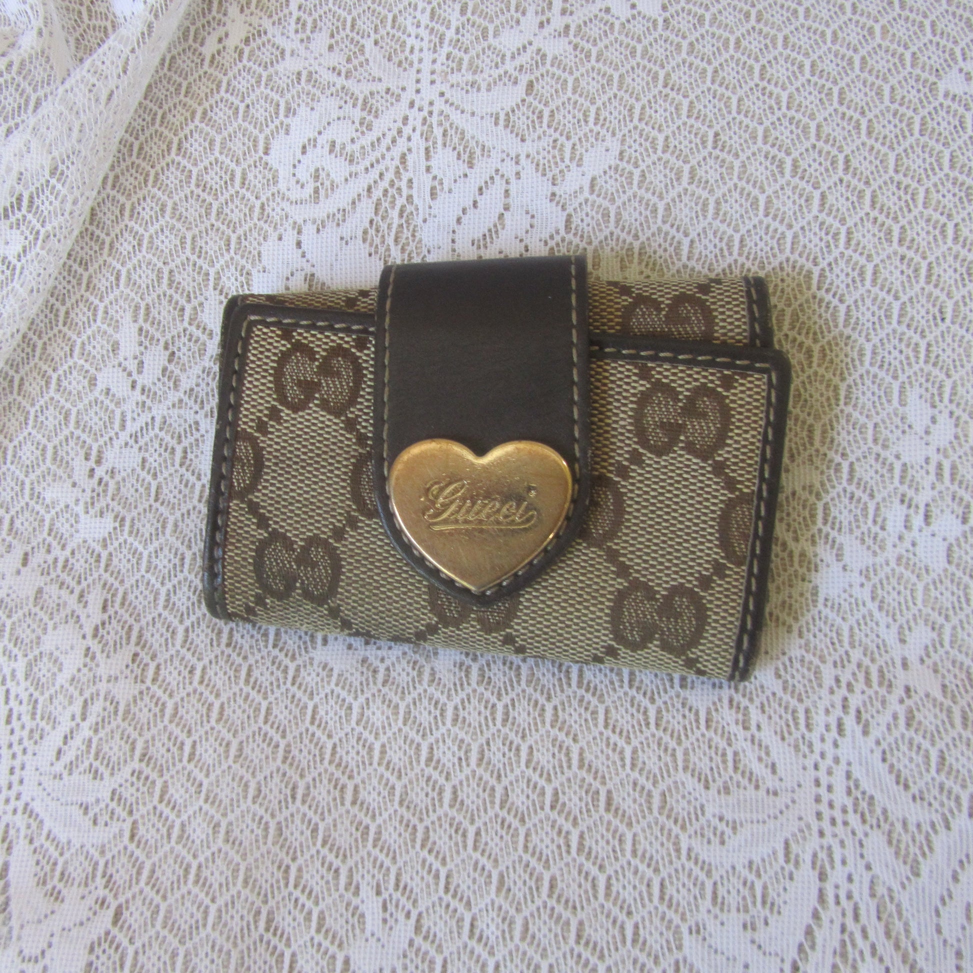 Small Gucci wallet with heart emblem on a lace background