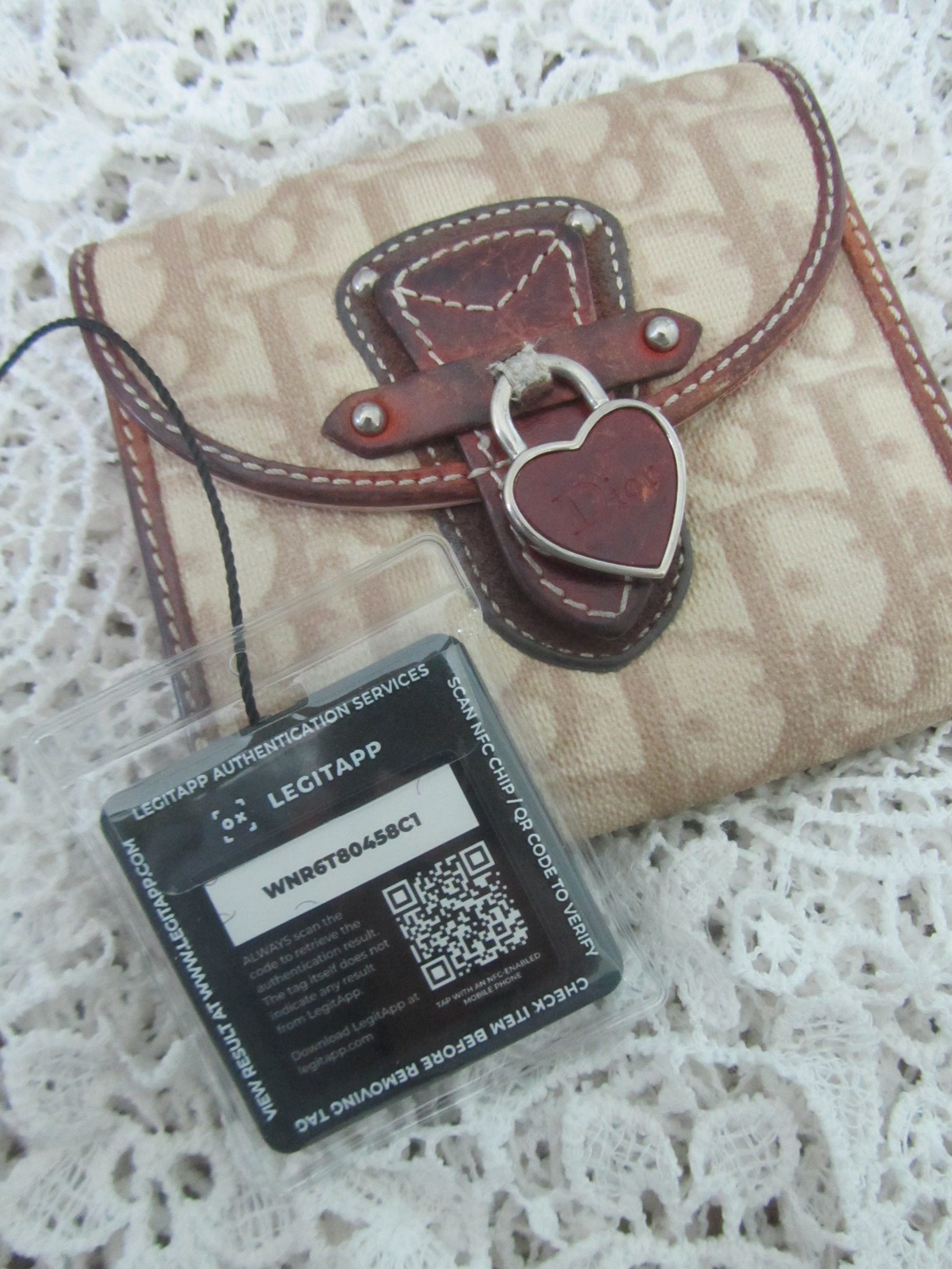 Beige leather wallet with brown accents on a white lace background