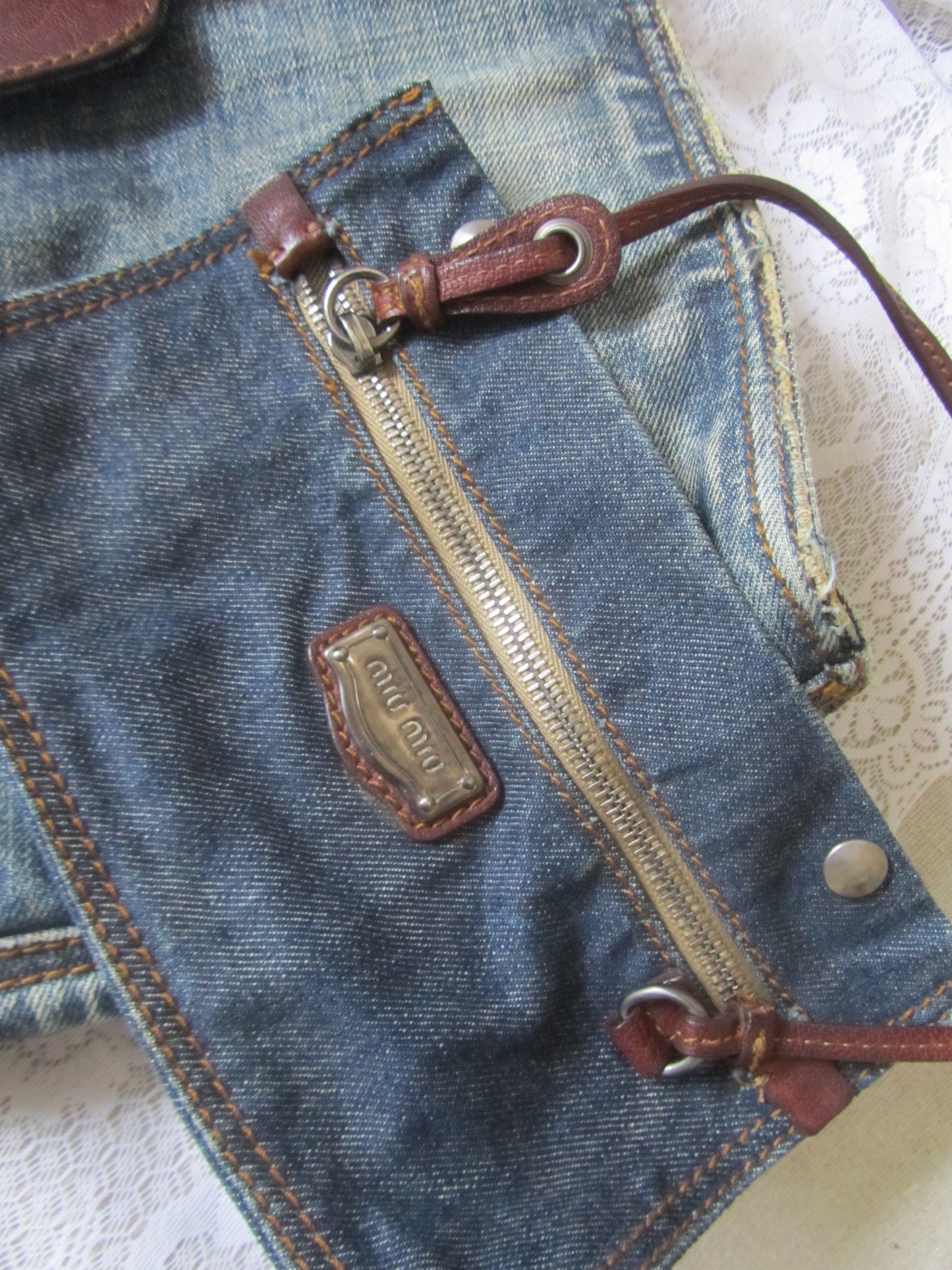 Close-up of a blue denim bag with a zipper and brand logo.