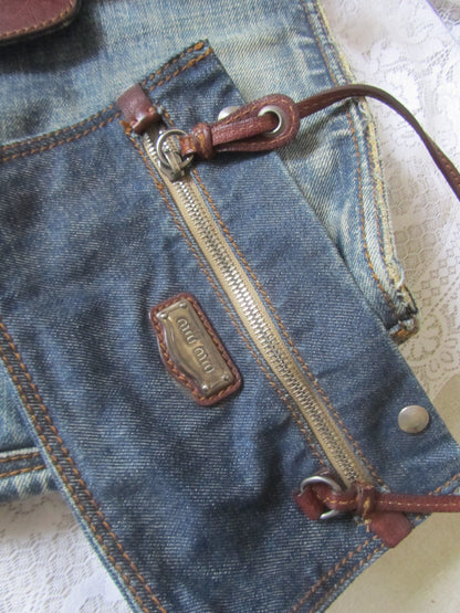 Close-up of a blue denim bag with a zipper and brand logo.