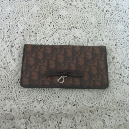 Brown textured wallet with a silver D clasp on a white lace background