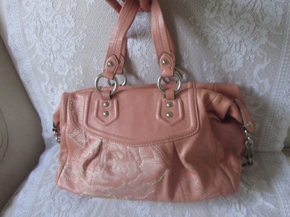 Pink handbag with lace detailing on a textured white surface
