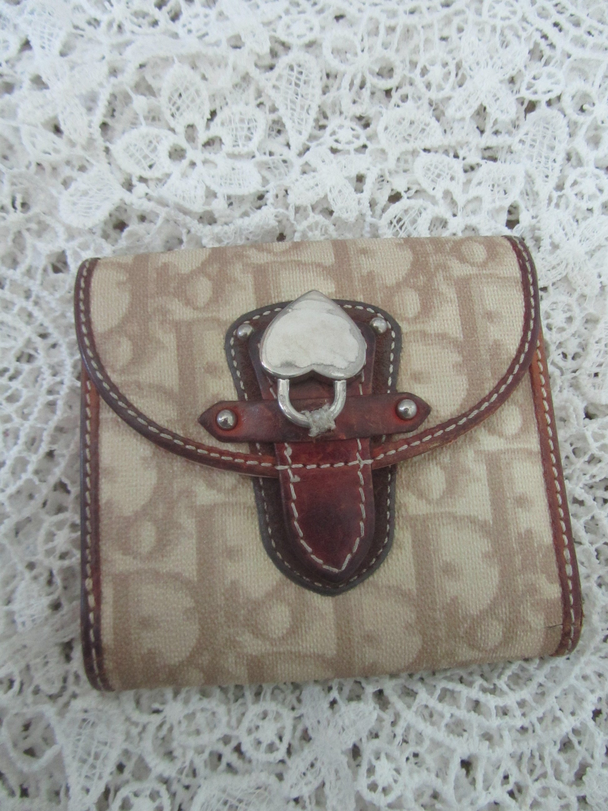 Beige wallet with brown leather buckle on a lace background