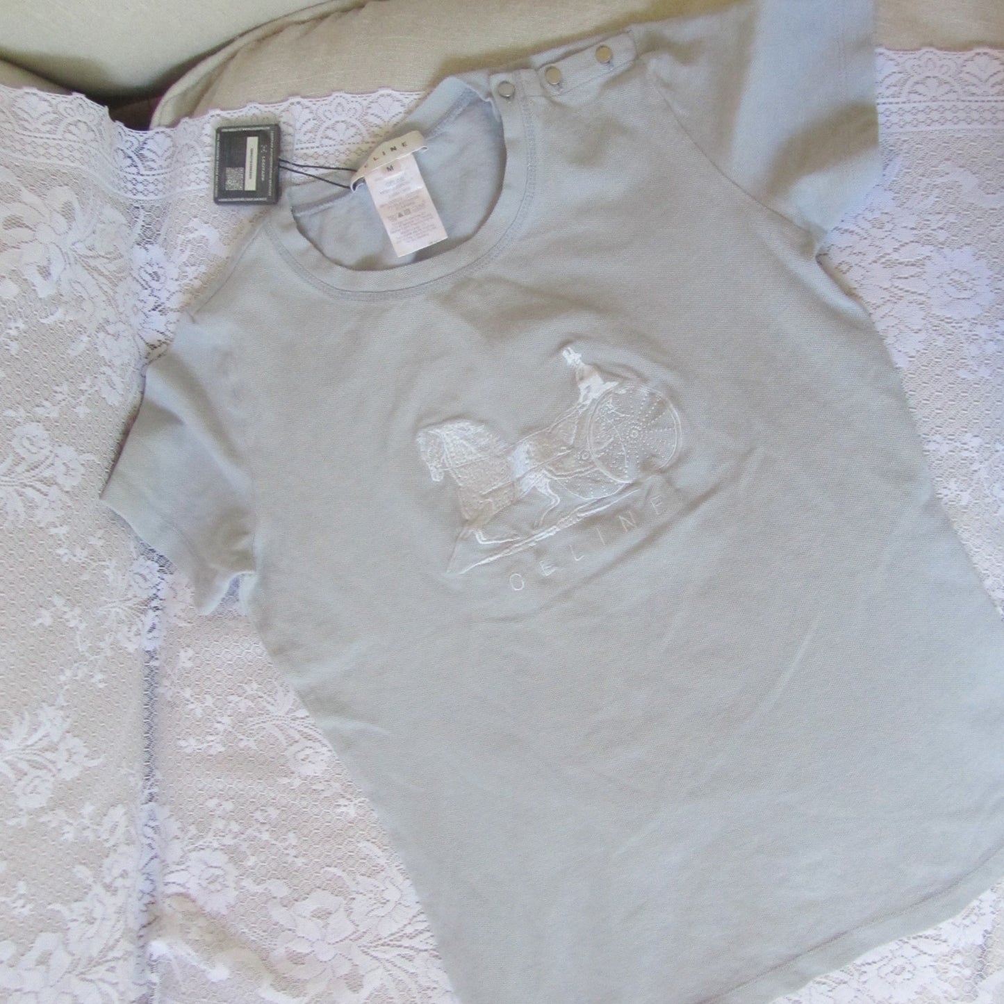 Light gray t-shirt with lace detail on a white surface