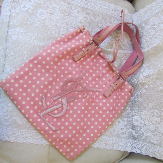 Pink polka dot bag with a logo on a white textured surface