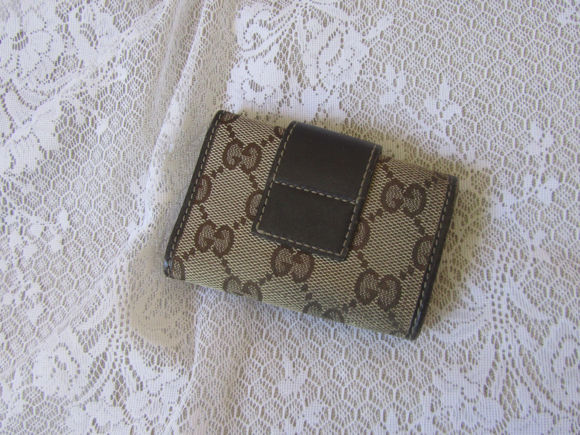 Small wallet with brand logo on a lace fabric background