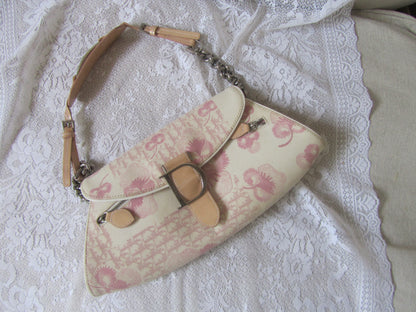 Floral patterned handbag with beige strap on a textured white surface