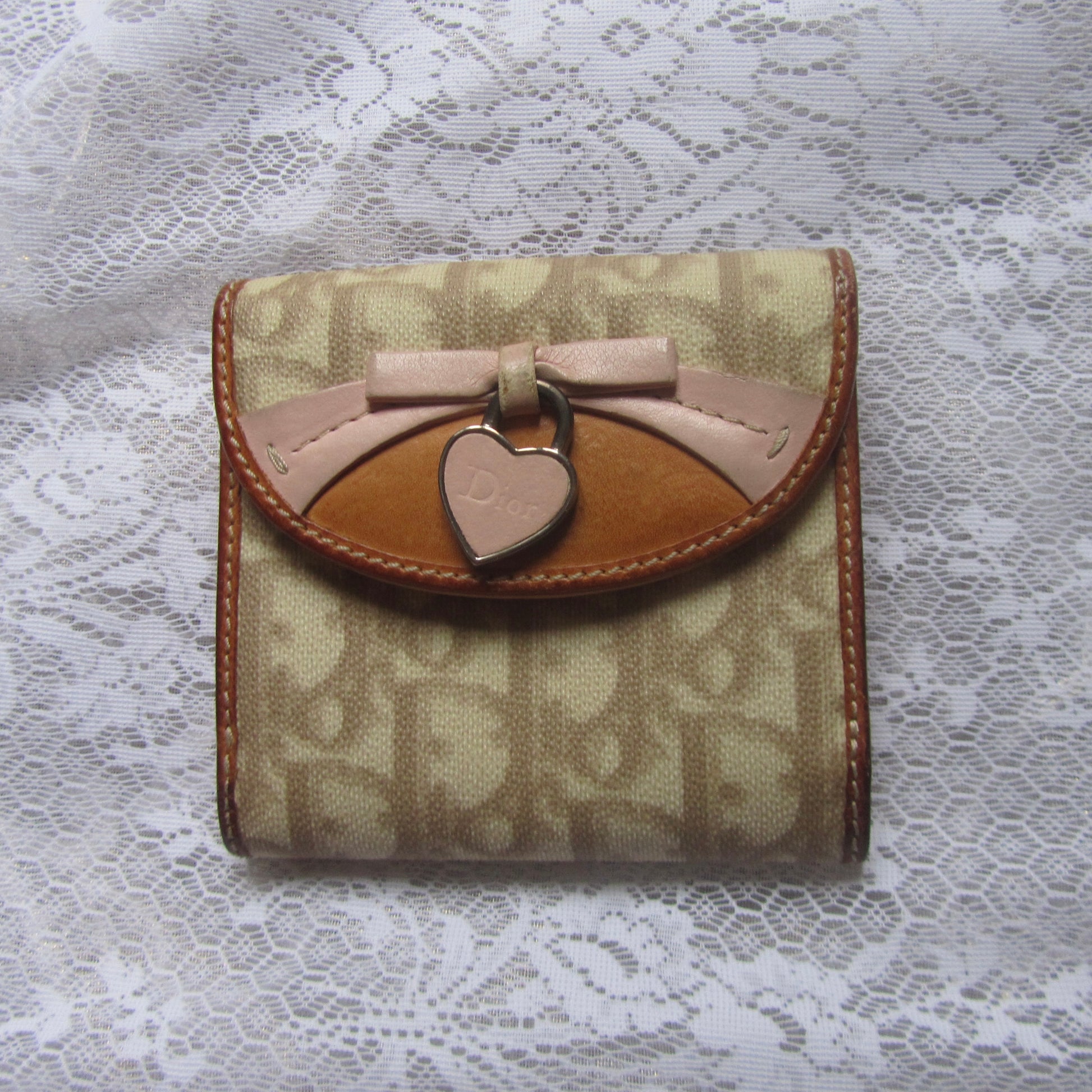 Small wallet with a bow and heart charm on a lace background