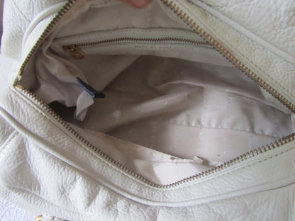 Close-up of a white quilted handbag with a gold zipper.